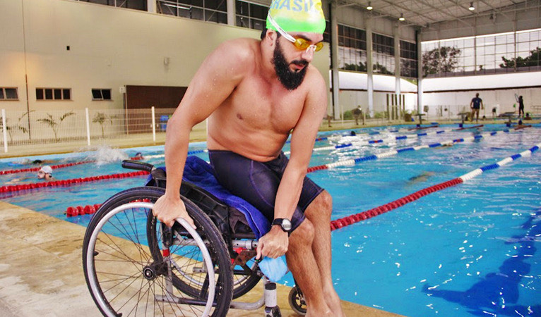rapaz de cadeira de rodas na frente de uma piscina olimpíca